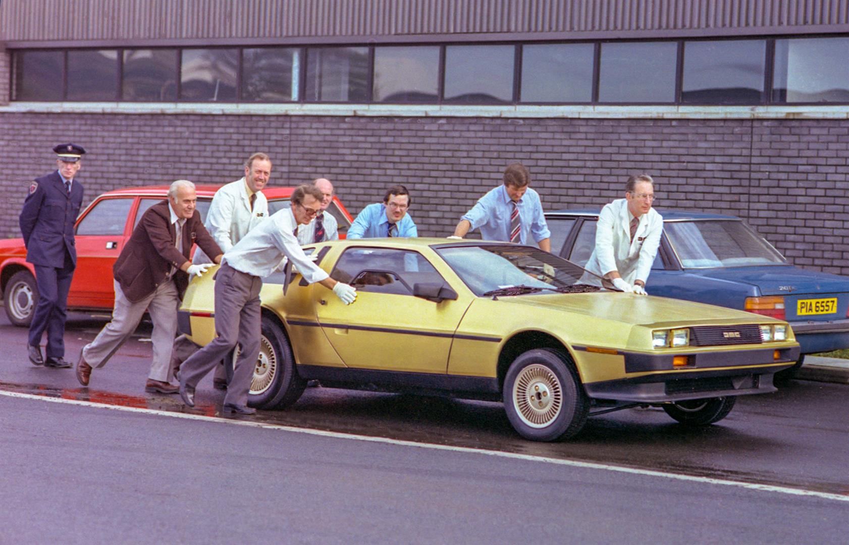 Moving the Gold car, with Tony McDade at rear and Dick Kendall second from the left | DeLoreanDirectory.com